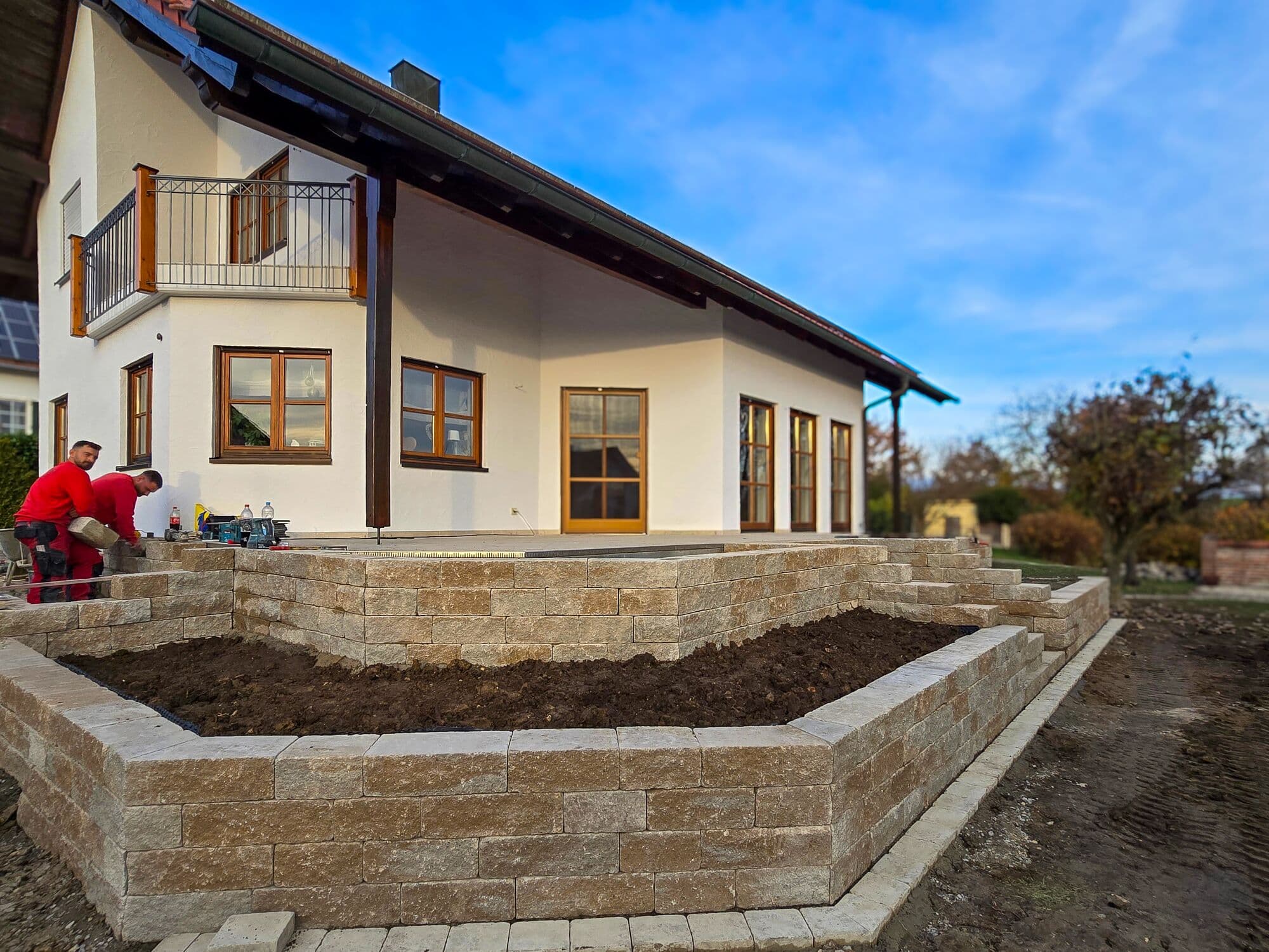 Natursteinmauer als Hochbeet-Einfassung vor einer Terrasse